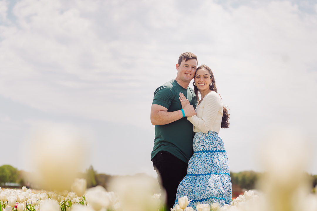 Engaged couple hugging in tulip field with flowers in foreground